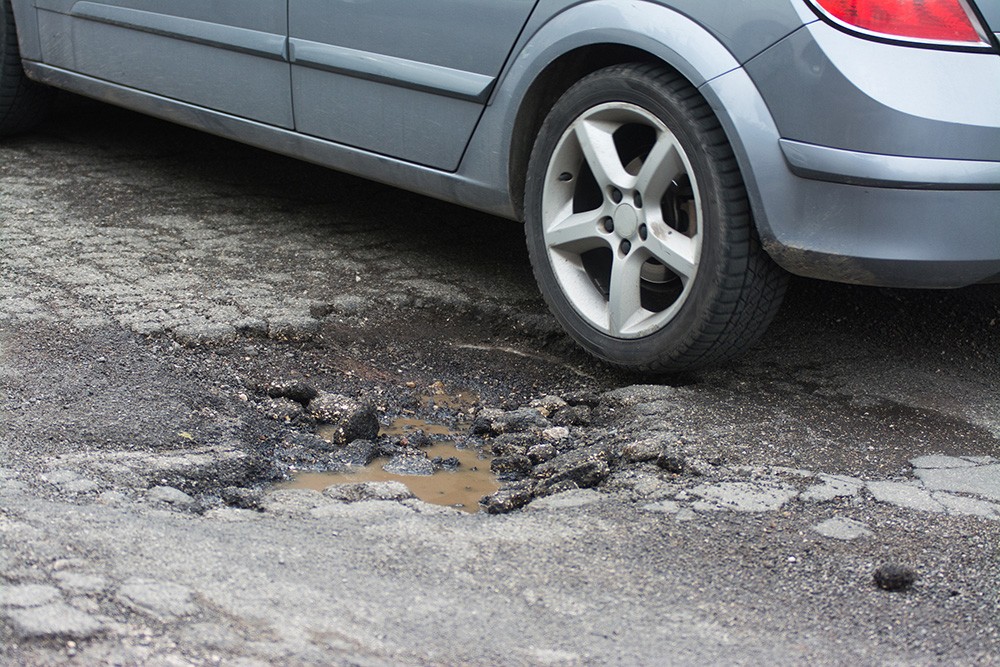 Pot-holed roads wreak havoc on vehicle alignment Car driving over pothole
